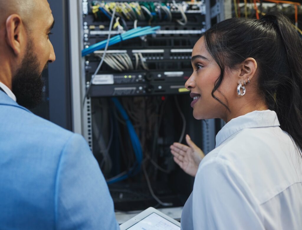 two network management professionals working in server room